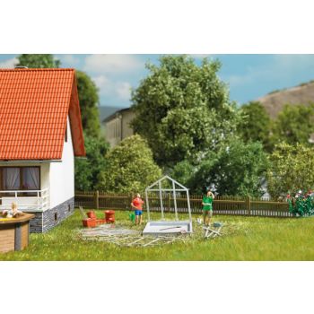 Gewächshausaufbau: Mann mit Bedienungsanleitung und Frau die gemeinsam ein Gewächshaus aufbauen, Bausatz für ein verglastes Gewächshaus und Zubehör