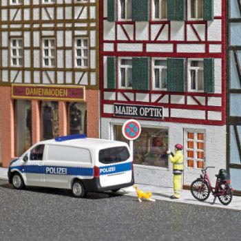 Anzeigenhauptmeister, ausgestattet mit Fahrrad und Warnschutzkleidung fotografiert er Autos im Parkverbot, mit Polizeiauto, Fahrrad und Figur