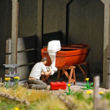 Boot reparieren, Bootsmechaniker, der einen Außenbordmotor instand setzt, mit Boot, Reparaturböcken, Werkzeugwagen und Werkzeugkiste