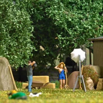 Model mit Heugabel bei der Heuernte: Heuhaufen, Strohballen, Säcke und Stallwerkzeug