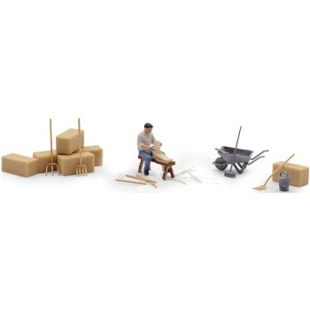 Holzschnitzer, der Holzschnitzer hat sein Werkstück auf der Schnitzbank fixiert. Holzstäbe, Heuballen, Schubkarren und Werkzeug