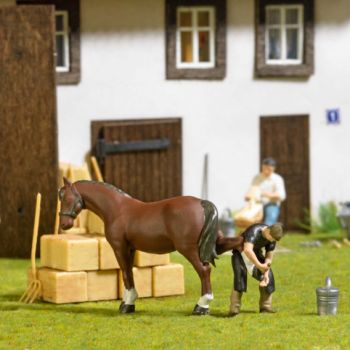 Hufschmied, der Hufschmied bearbeitet die Hufe des großen Braunen. Action-Set mit Hufschmied, Pferd, 6 Heuballen, Stallwerkzeug, Eimer, Werkzeugkiste